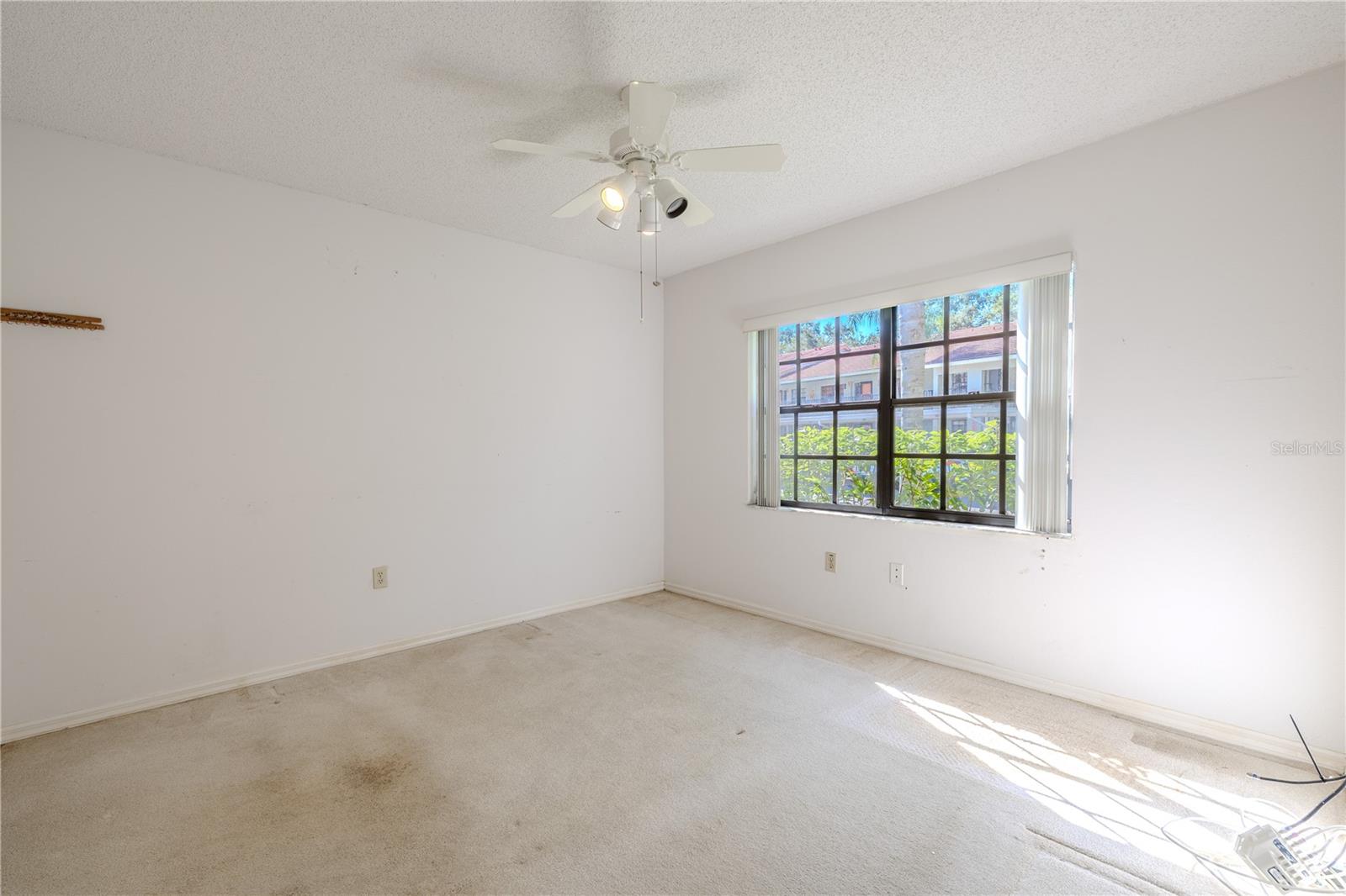 This second bedroom enjoys soft natural light from its large window, creating a warm and inviting atmosphere.