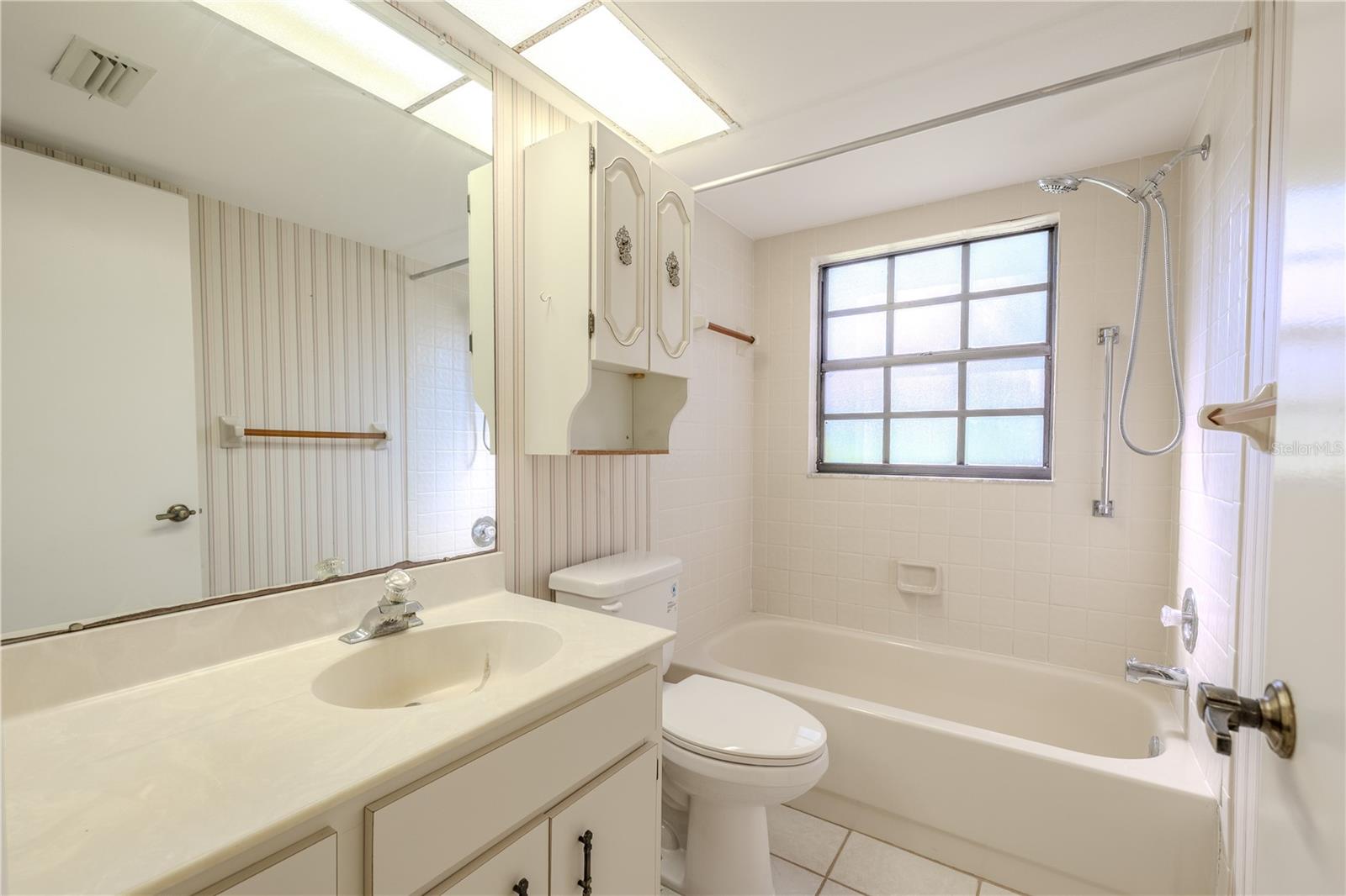 A traditional tub-and-shower combination pairs with a window that brightens the bath and gives it an open, fresh feel.