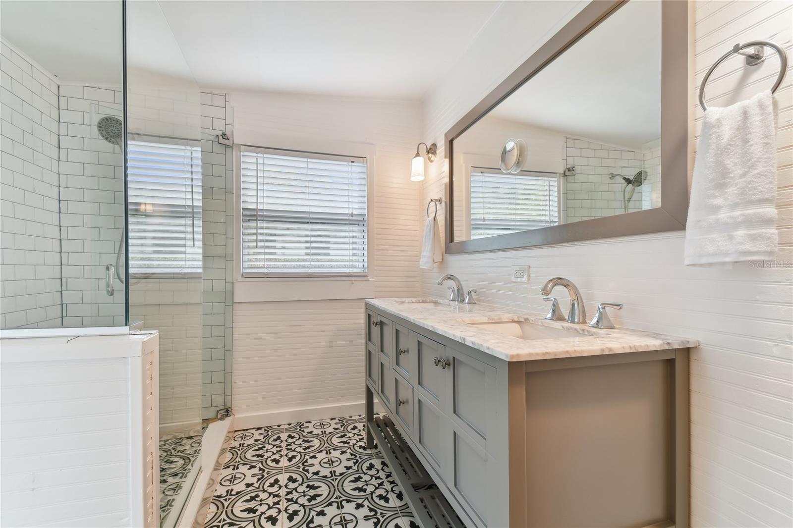Primary bath has double vanity and large glass enclosed shower