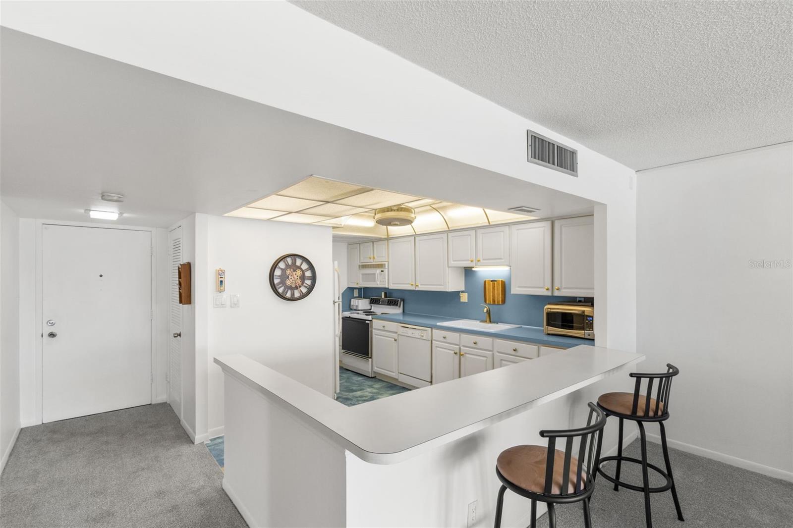 THE BRIGHT KITCHEN IS DESIGNED WITH A CASUAL SNACK BAR FOR DINING AND ENTERTAINING