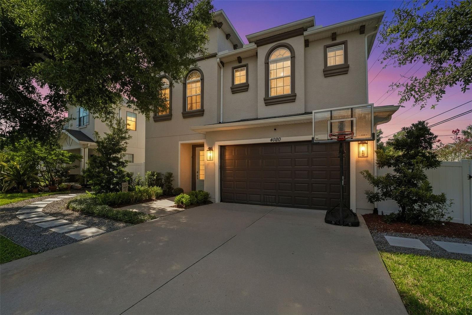 Stunning two-story façade highlighted by arched windows, elegant trim details, and warm evening lighting for inviting curb appeal.