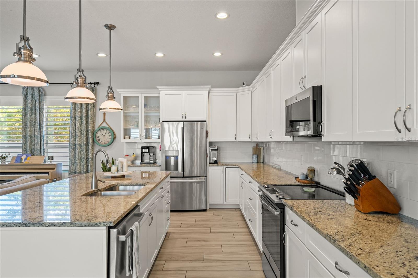 Modern kitchen with granite countertops, stainless steel appliances, pendant lighting, and an oversized island with seating.