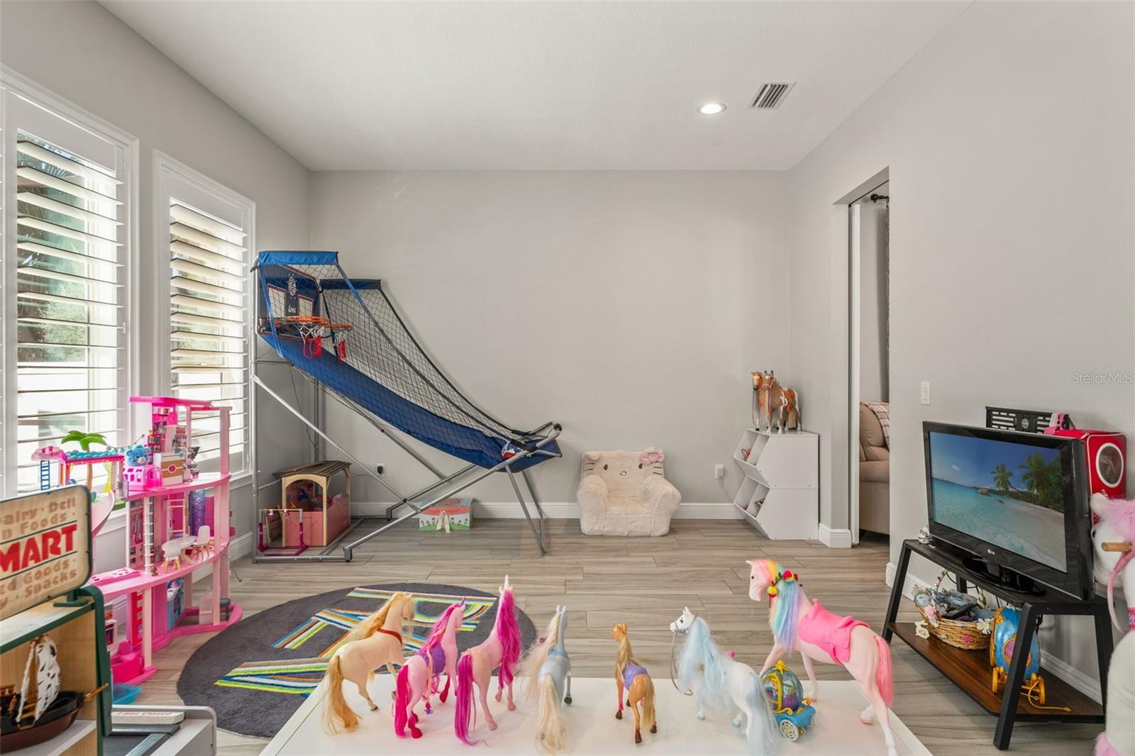 Bright and versatile bonus space with plantation shutters and wood-look tile, ideal for play or recreation.