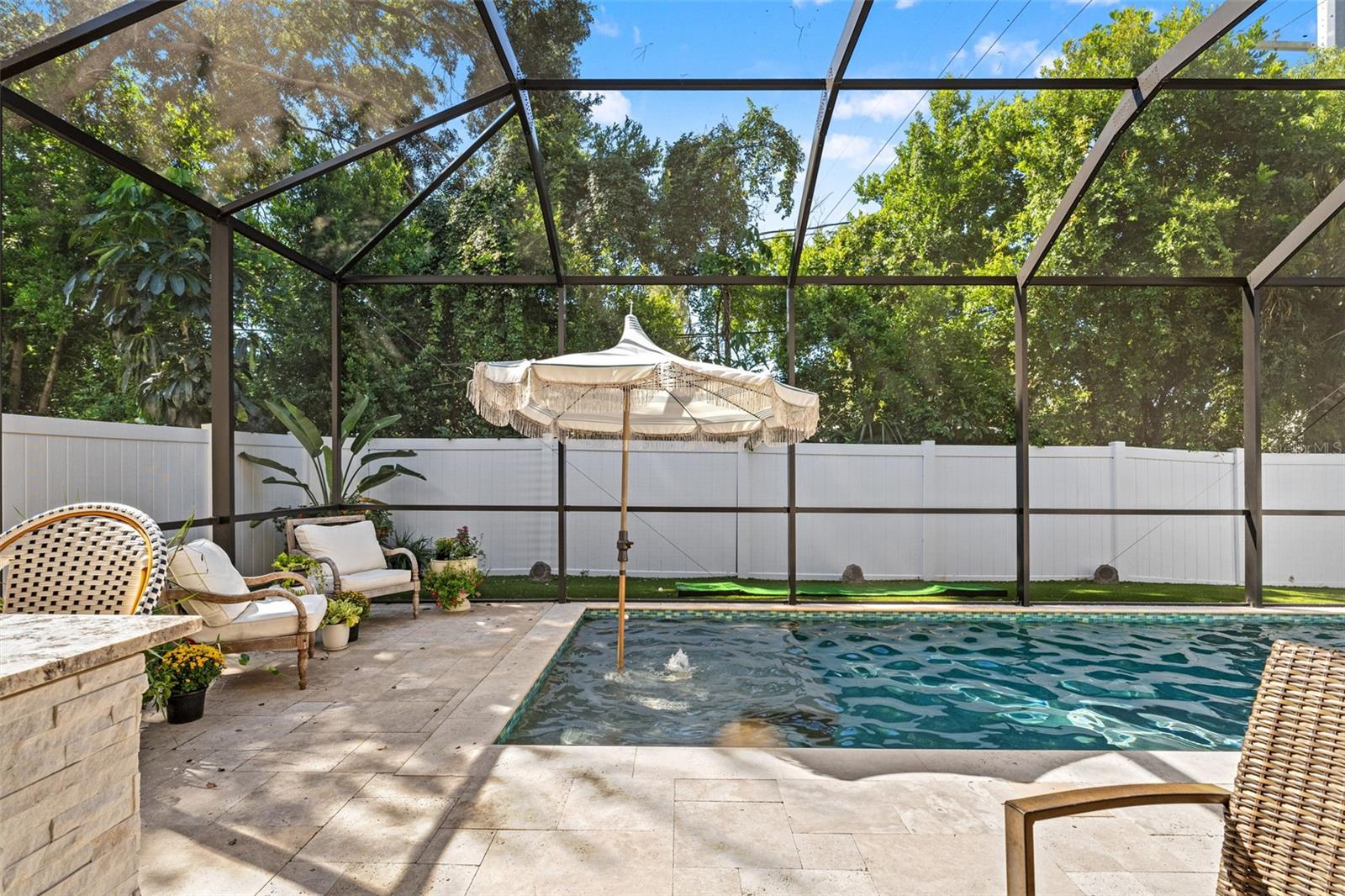 Enclosed pool with umbrella shade and water feature, offering year-round enjoyment.