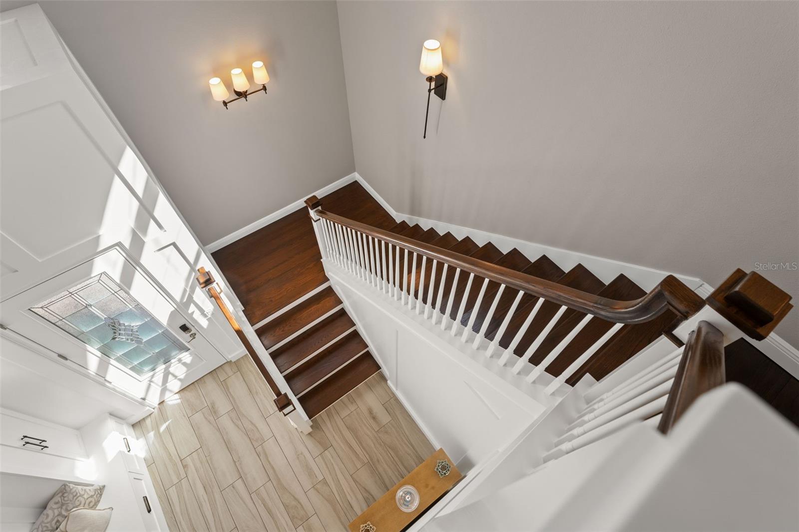 Dramatic view from the landing highlighting wood treads, crisp white trim, and abundant natural light.