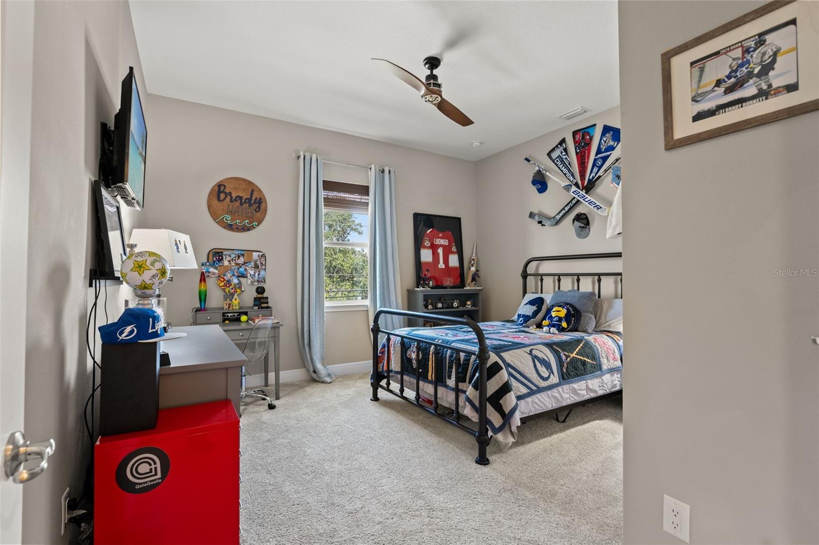 Bright secondary bedroom with large window, ceiling fan, and space for personalized décor.