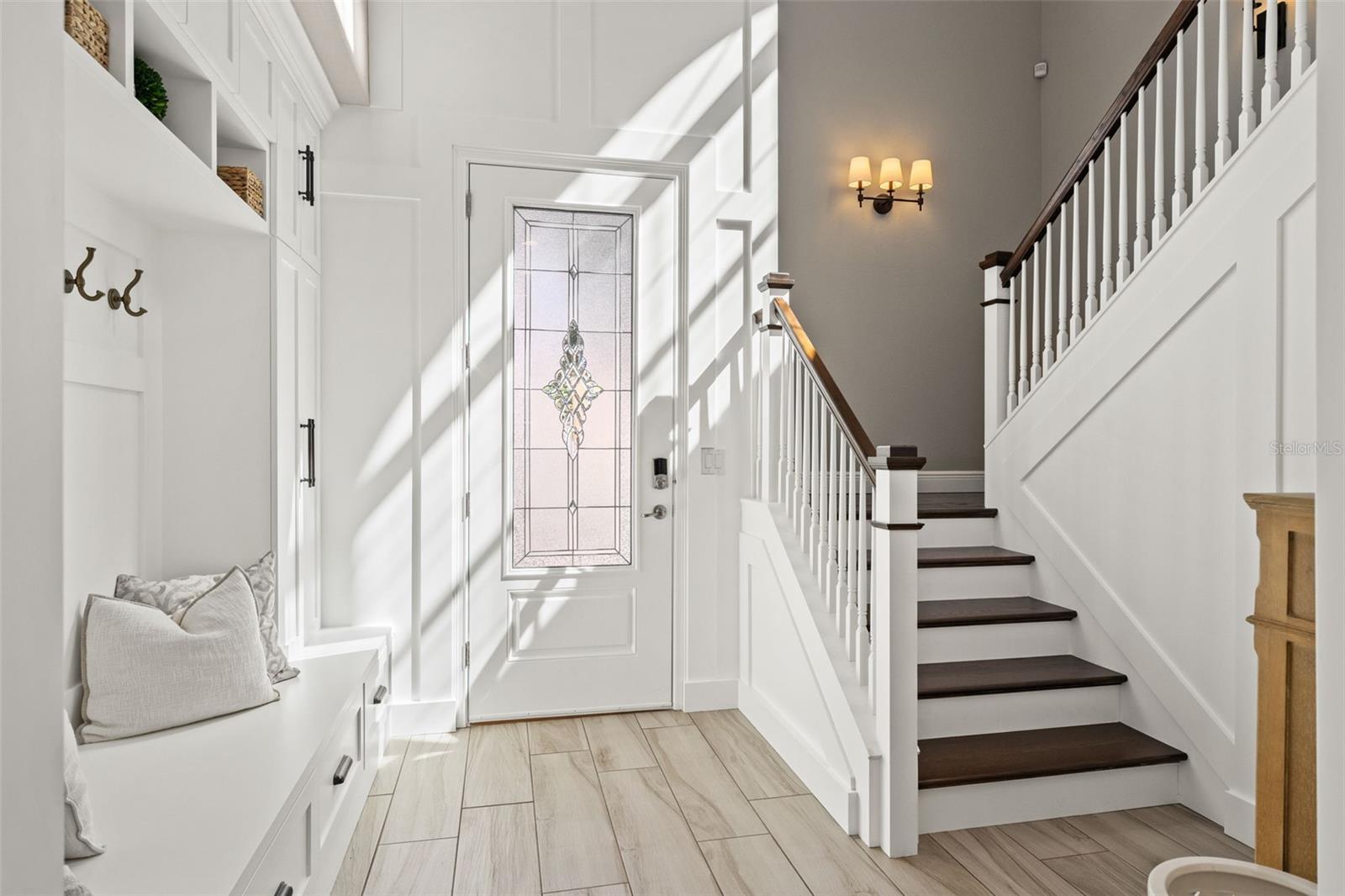 Soaring ceilings with abundant natural light, elegant wainscoting, and a custom built-in bench with storage.