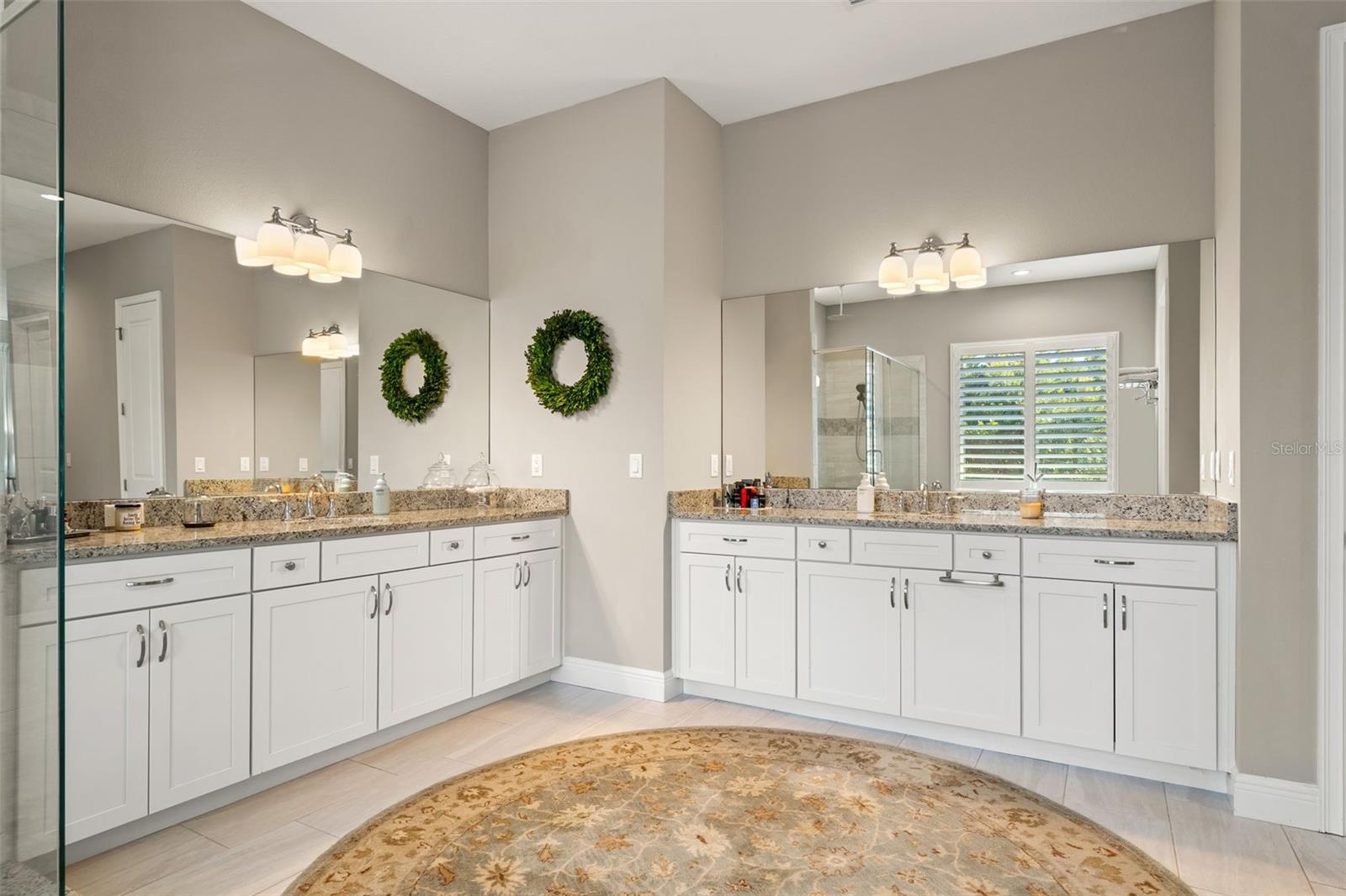 Dual vanities with granite countertops, abundant cabinetry, and expansive mirrors.