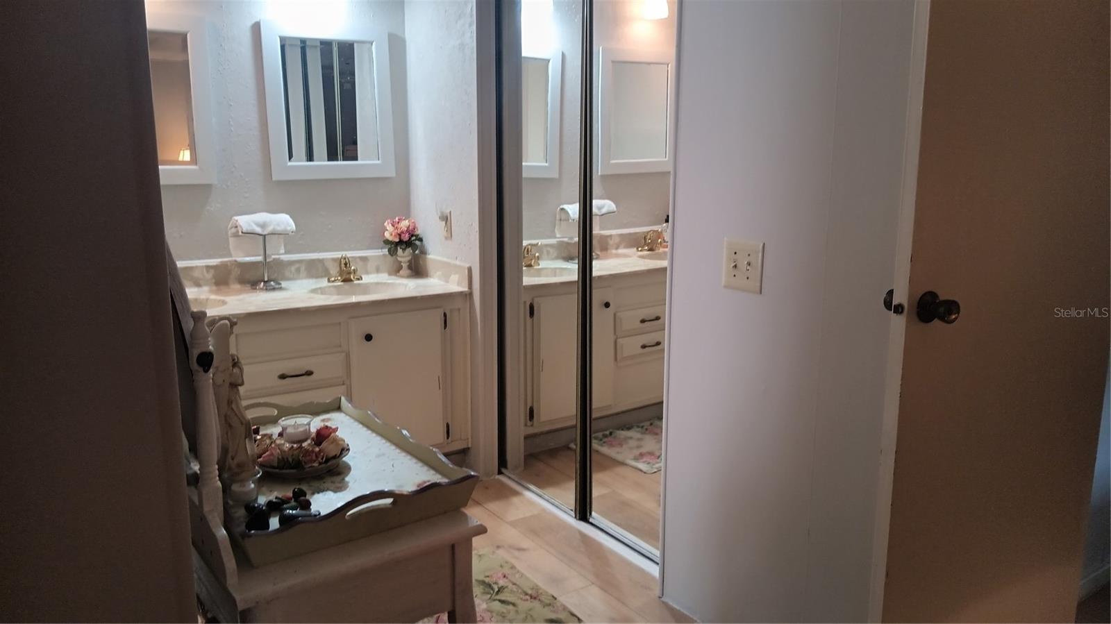 Dressing area with double sinks and mirrored closet doors