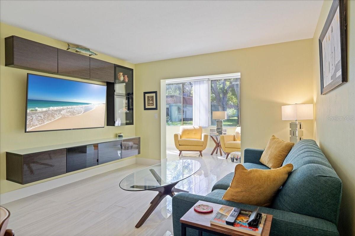 The spacious living room includes a floating entertainment center and flows seamlessly into the finished lanai/sunroom