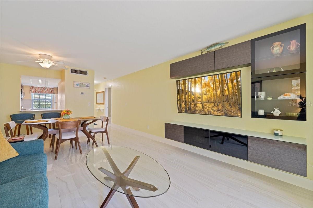 The spacious living room includes a floating entertainment center and flows seamlessly into the finished lanai/sunroom