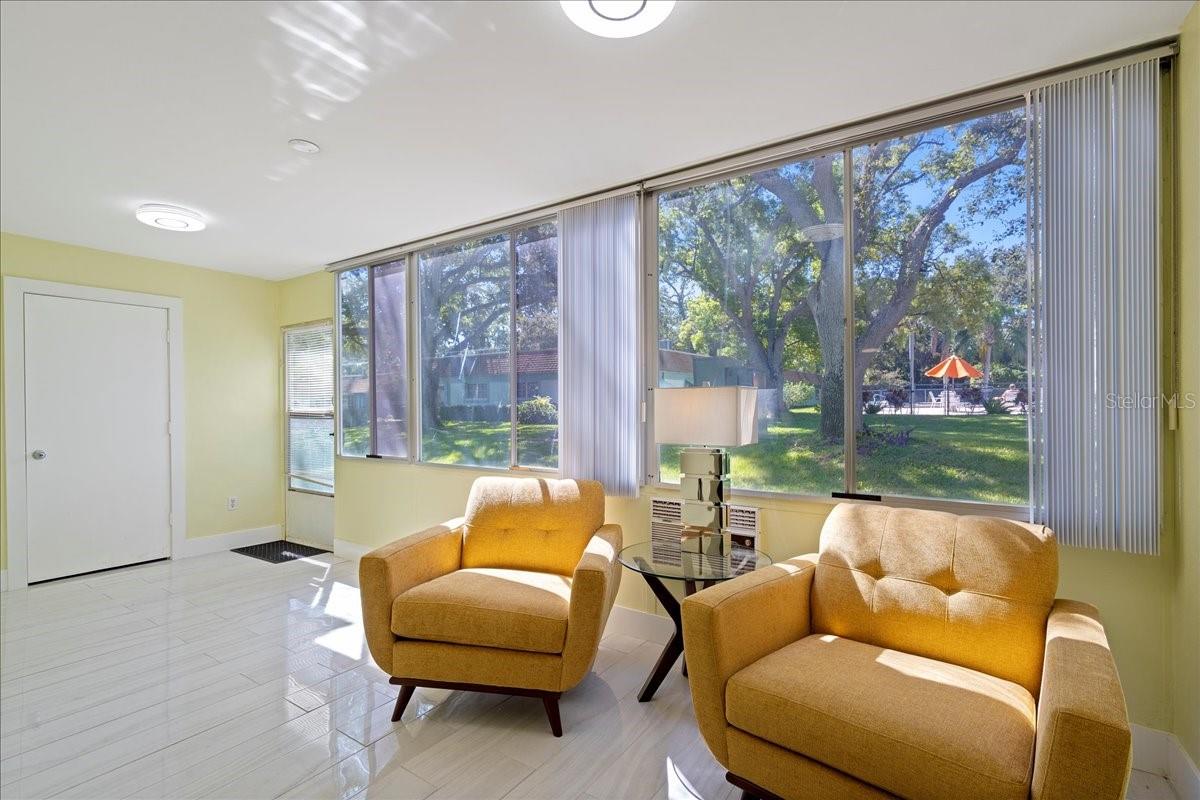 finished lanai/sunroom, where large windows stretch across the back of the unit, filling the space with natural light and framing tranquil views of mature oak trees and greenspace. Complete with a storage closet, this inviting area offers the perfect place to relax and unwind.