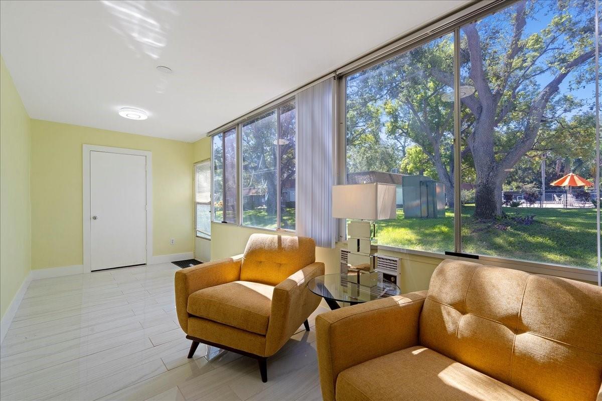 finished lanai/sunroom, where large windows stretch across the back of the unit, filling the space with natural light and framing tranquil views of mature oak trees and greenspace. Complete with a storage closet, this inviting area offers the perfect place to relax and unwind.