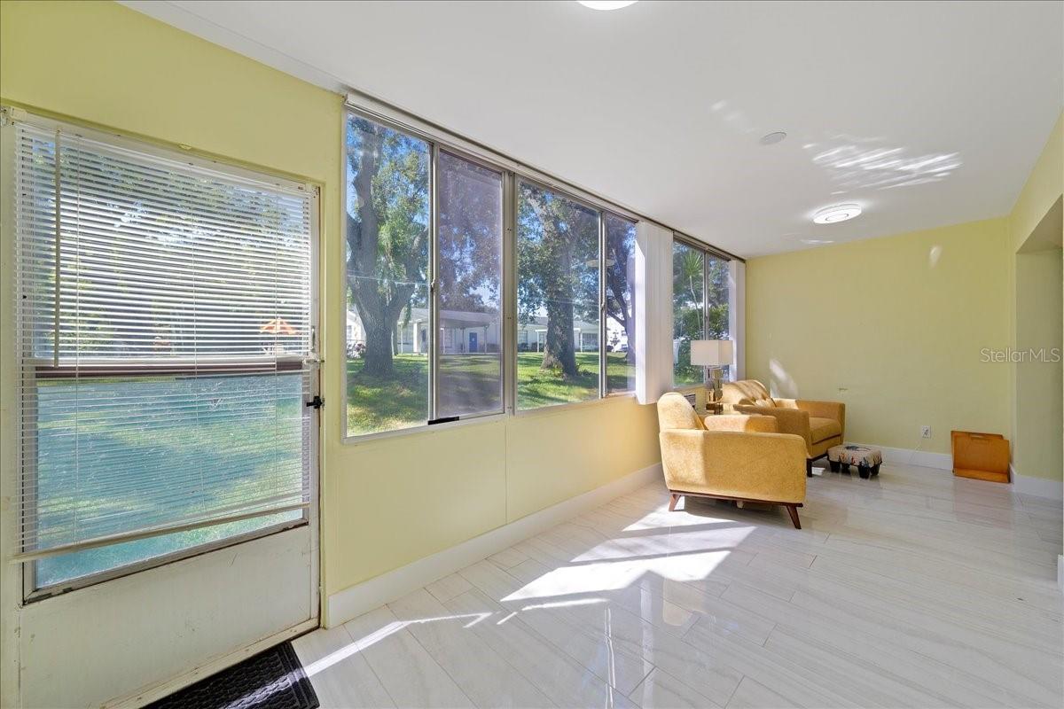 finished lanai/sunroom, where large windows stretch across the back of the unit, filling the space with natural light and framing tranquil views of mature oak trees and greenspace. Complete with a storage closet, this inviting area offers the perfect place to relax and unwind.