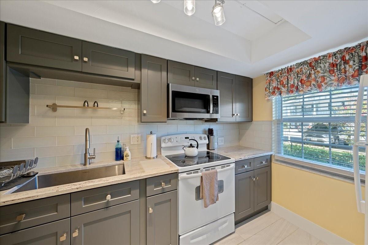 The updated kitchen boasts solid wood shaker-style cabinets, granite countertops, a large farmhouse sink, and a tasteful tile backsplash in clean, modern colors.