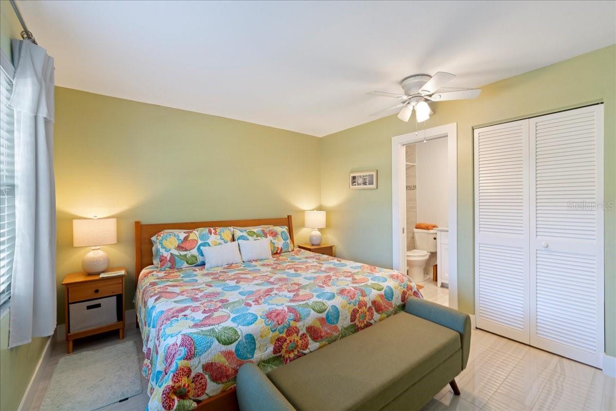 The bedroom is tucked away for privacy and includes a walk-in closet and an updated ensuite bathroom with a beautifully tiled shower and a stylish vanity with a granite countertop.