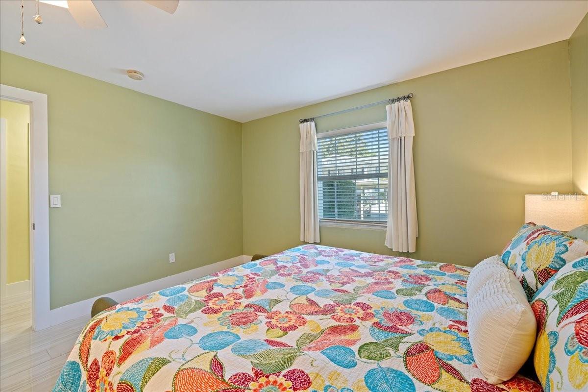 The bedroom is tucked away for privacy and includes a walk-in closet and an updated ensuite bathroom with a beautifully tiled shower and a stylish vanity with a granite countertop.