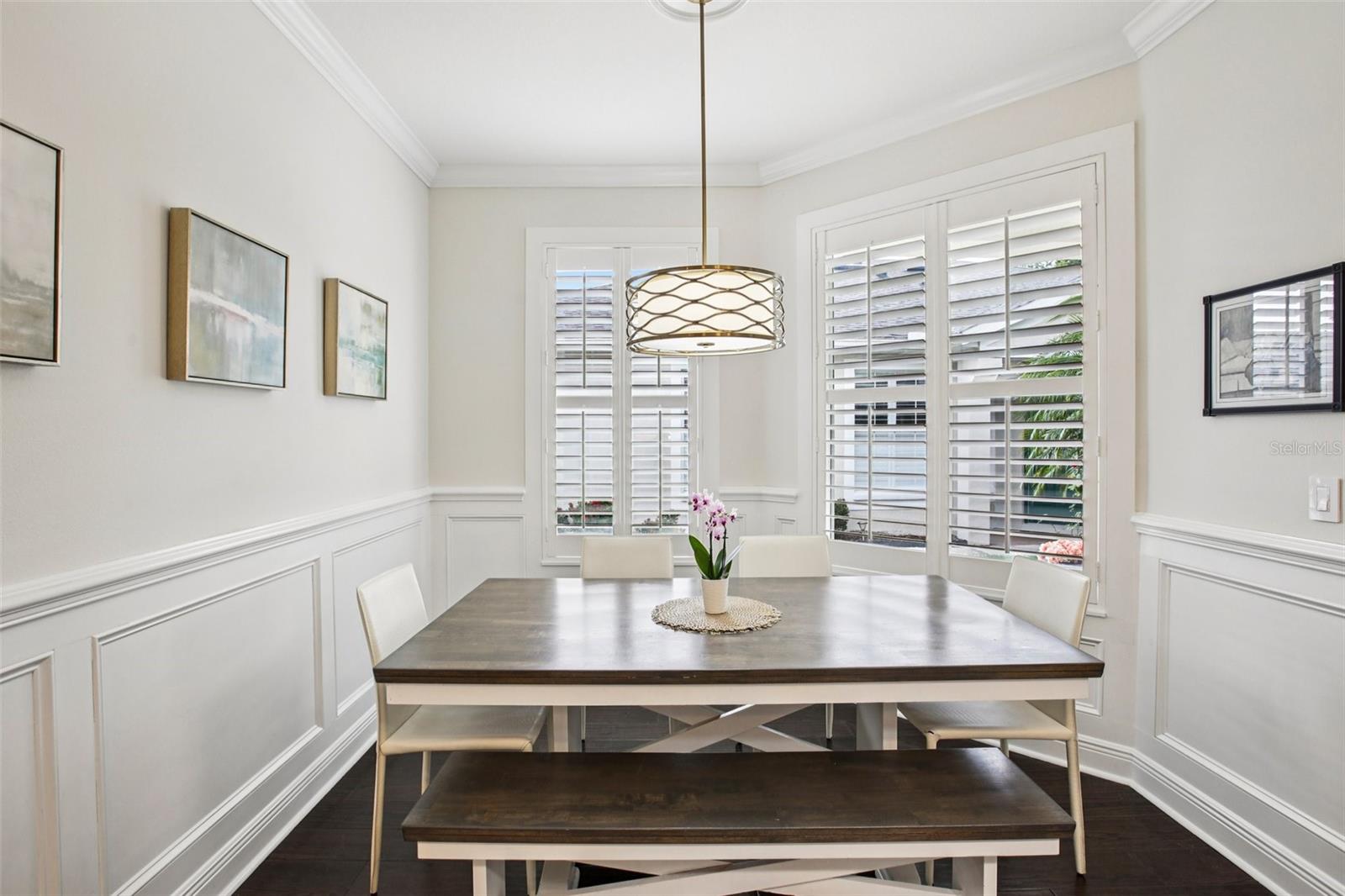 Dining area with wainscot trim and plantation shutters