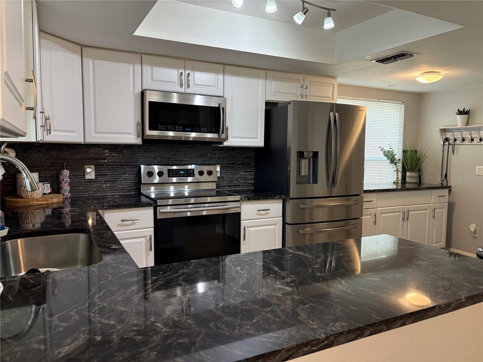 Notice the 6' of counter space next to the stainless steel refrigerator. Great for food prep or office area with lots of storage below!