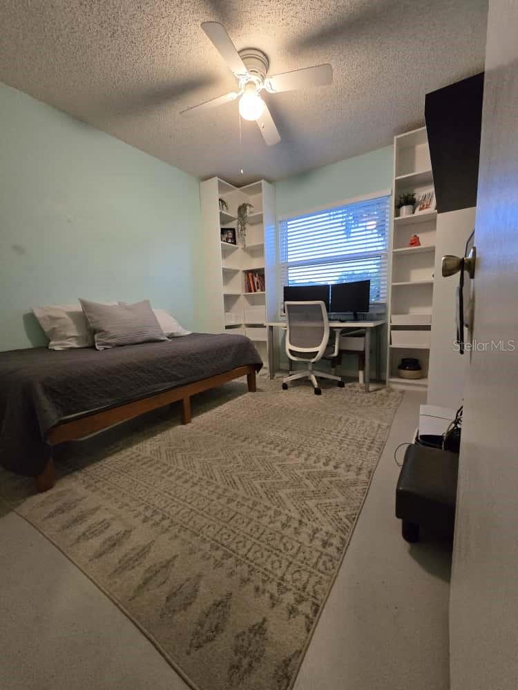 Third bedroom with high ceiling, ceiling fan and attached floor-to-ceiling bookshelves surrounding the window.  Makes a great area for computer or make-up mirror.