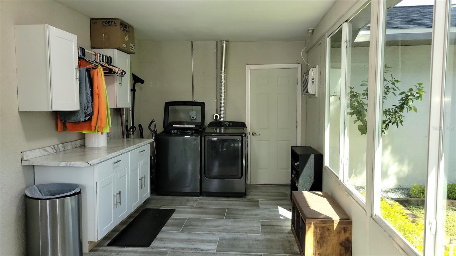 The opposite side of the gym area is the inside laundry. The additional cabinets, counter tops, and closet rack make it super easy to keep the laundry area organized. The door you see in the back of the photo opens to the 2 car garage.