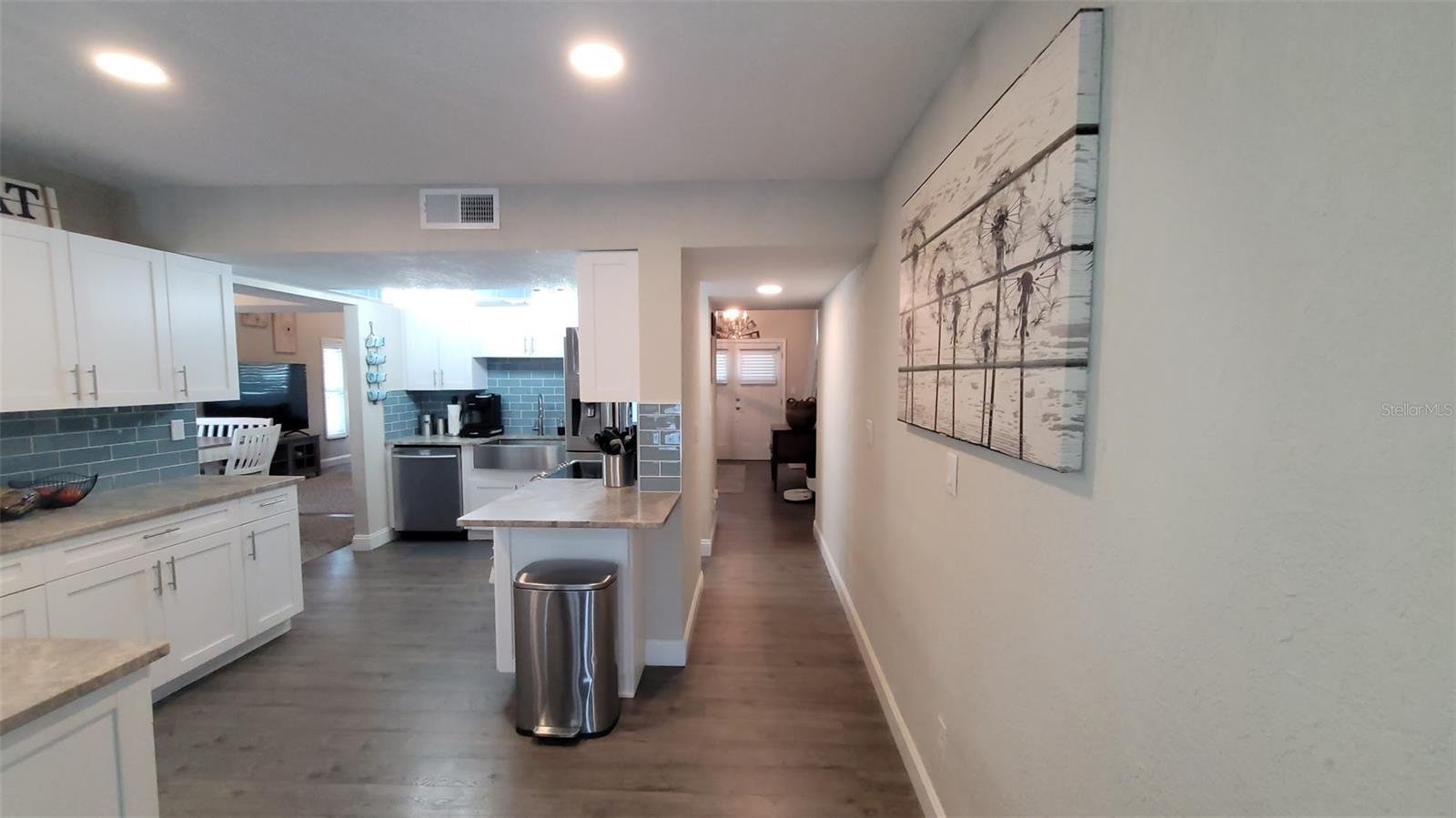 From this view of the kitchen, you can see the entry doorway for the front of the home as well as the hallway leading to it.