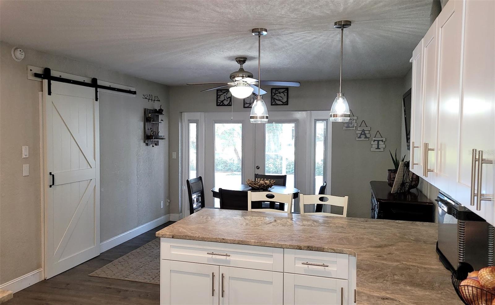 This view of the kitchen shows a barn door that leads out to the Laundry and gym area. The french doors straight ahead lead out to the pool.