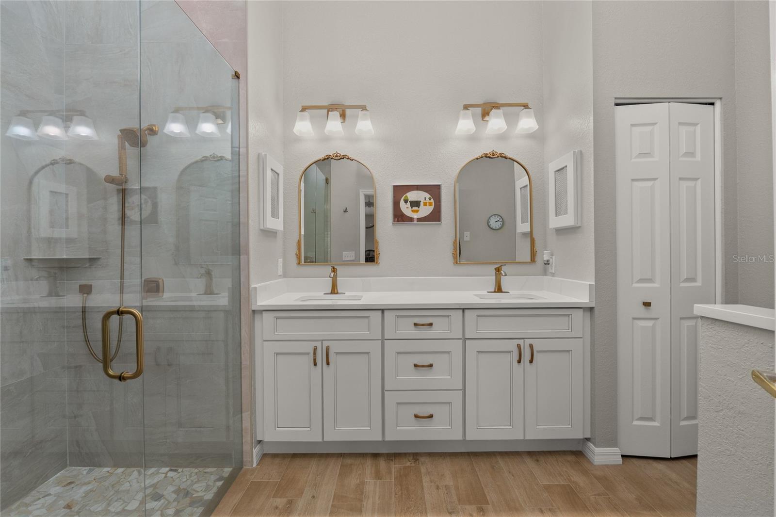 Bathroom updated with Floor to Ceiling Tile, new vanities, fixtures and lighting