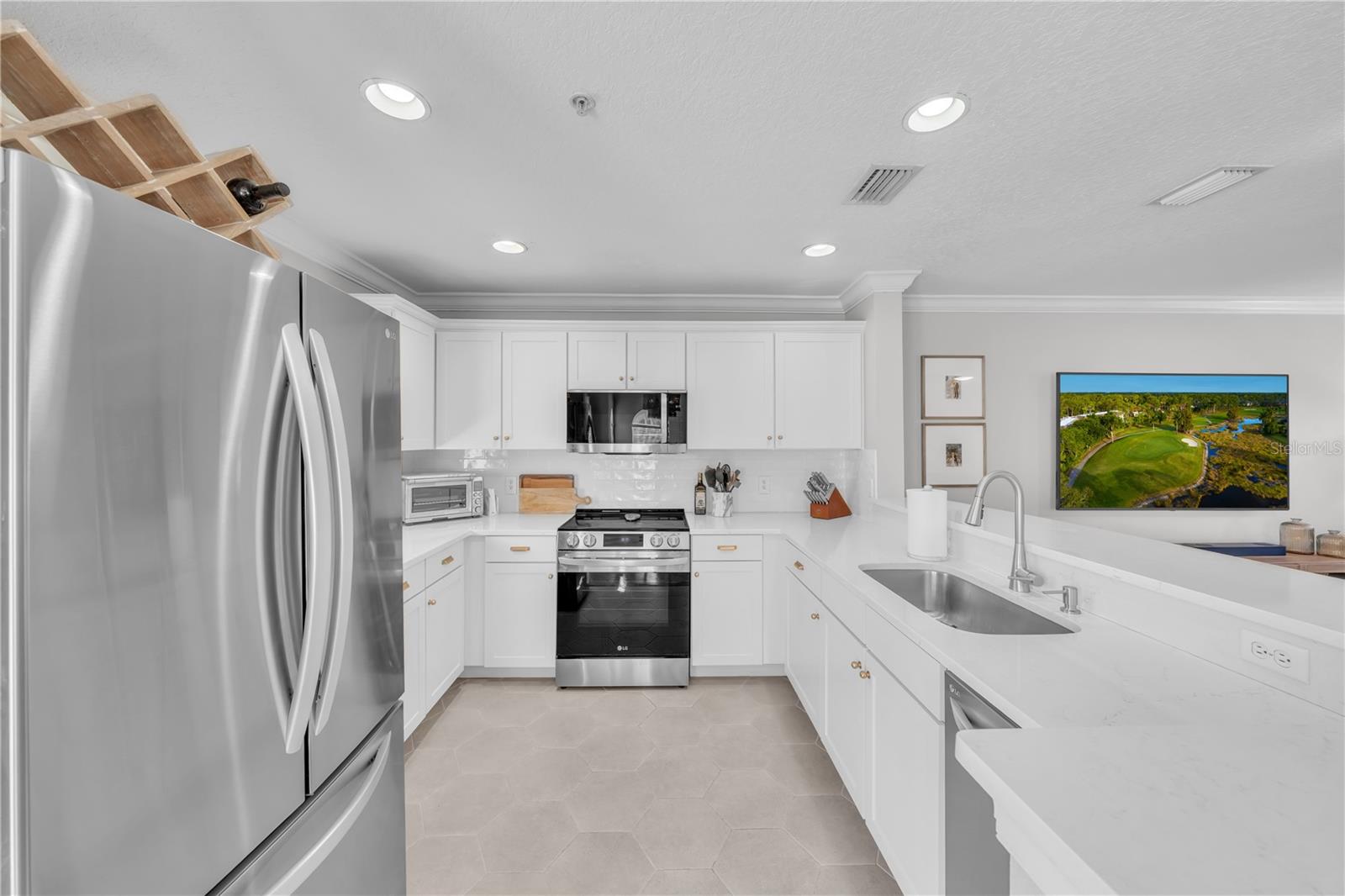 Fully updated kitchen with designer Quartz, Stainless Steel Appliances, breakfast bar seating, white wooden cabinetry, and recessed lighting