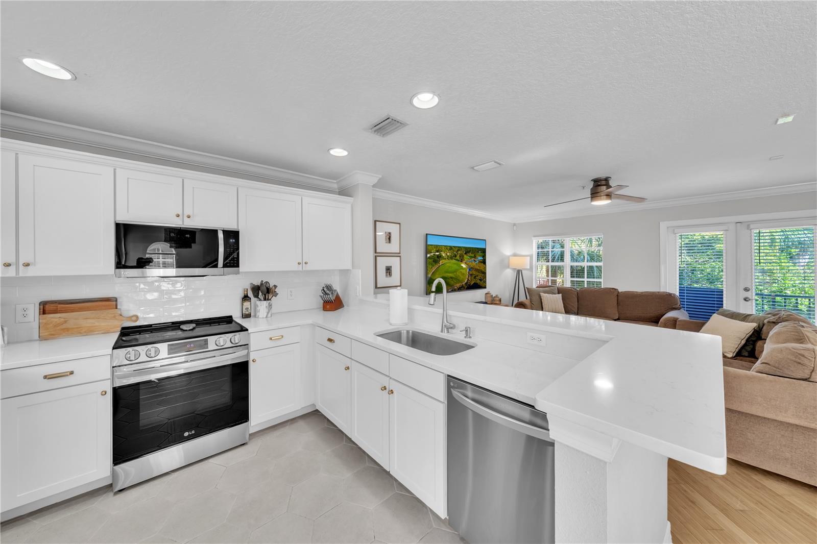 Fully updated kitchen with designer Quartz, Stainless Steel Appliances, breakfast bar seating, white wooden cabinetry, and recessed lighting
