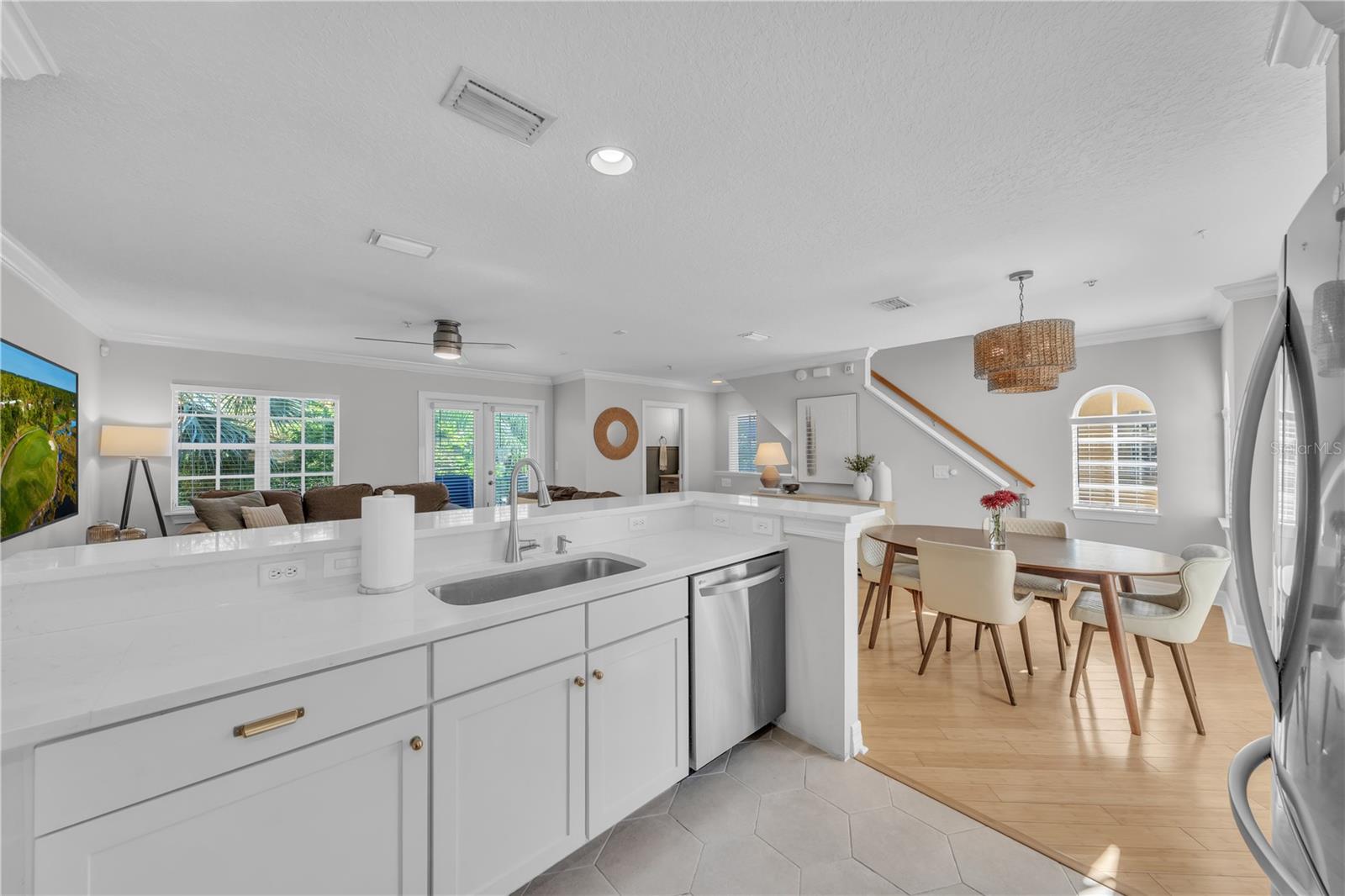 Fully updated kitchen with designer Quartz, Stainless Steel Appliances, breakfast bar seating, white wooden cabinetry, and recessed lighting
