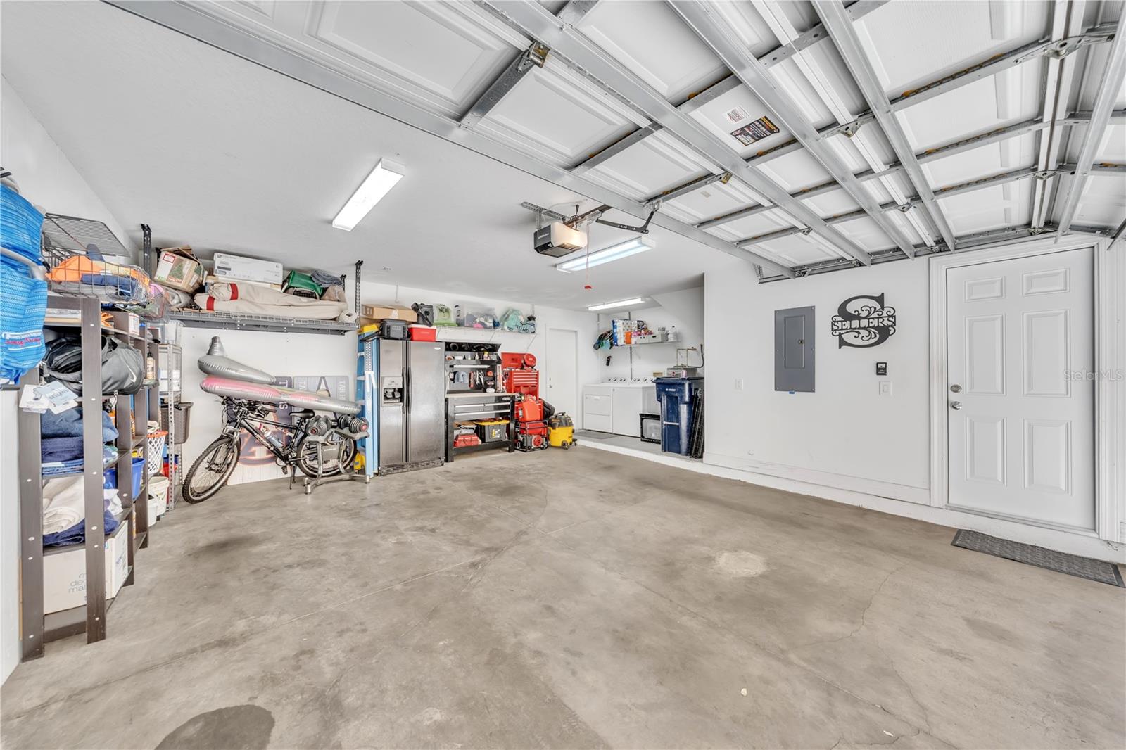Extra large two car garage with washer and dryer included, water heater, ceiling overhead racks, and rear exit to private back porch and pool
