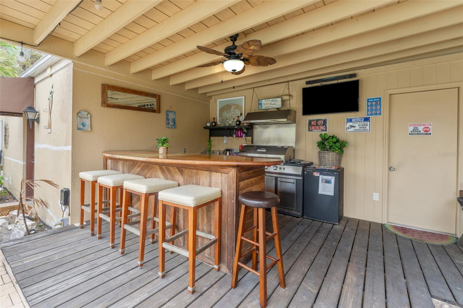 Outdoor kitchen with gas grill, fridge, sink, and food prep space. Door to apartment #3.