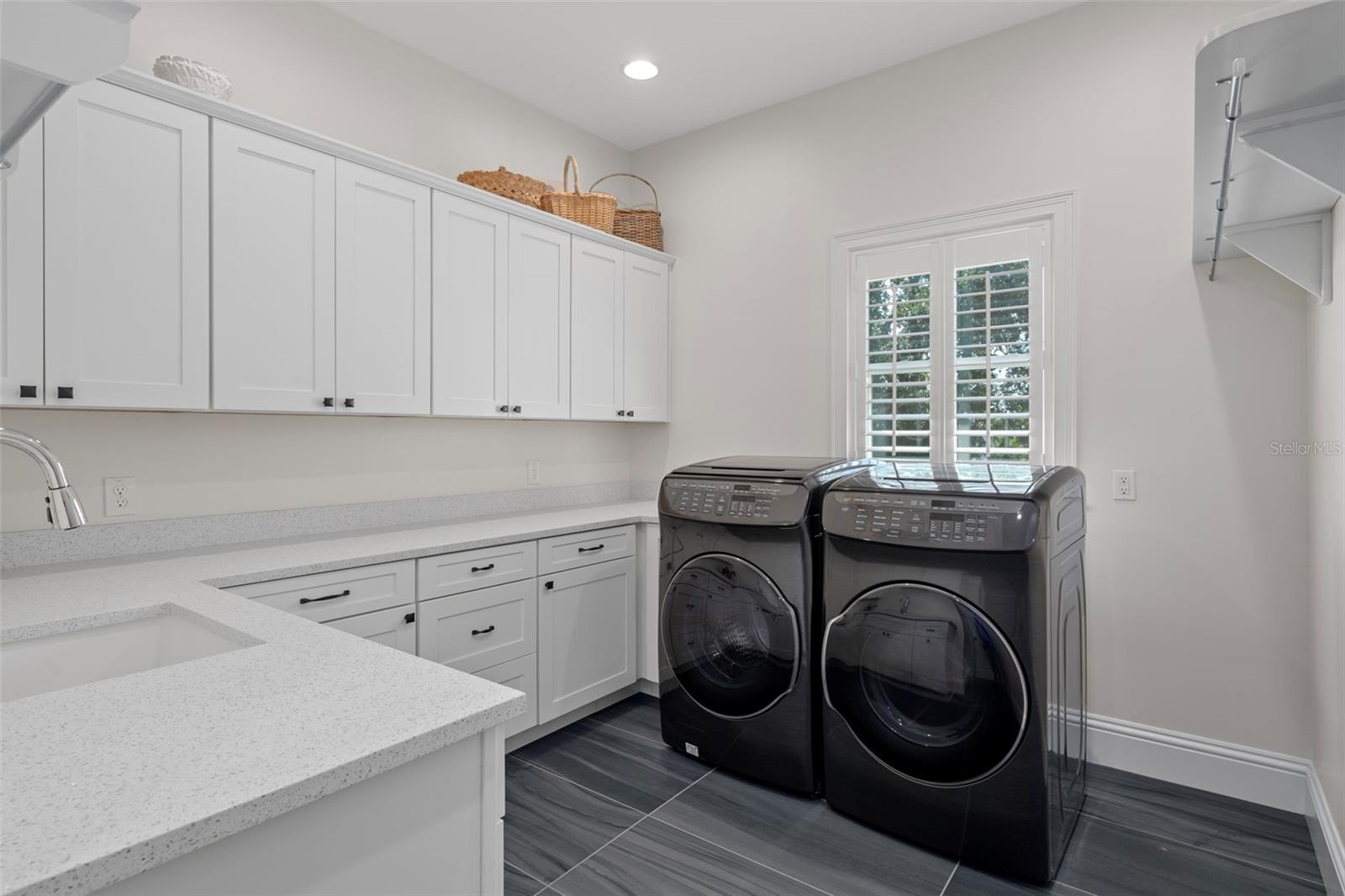 Convenient upstairs laundry room with plenty of cabinetry, counter space for folding, a rinse sink, and hanging space.