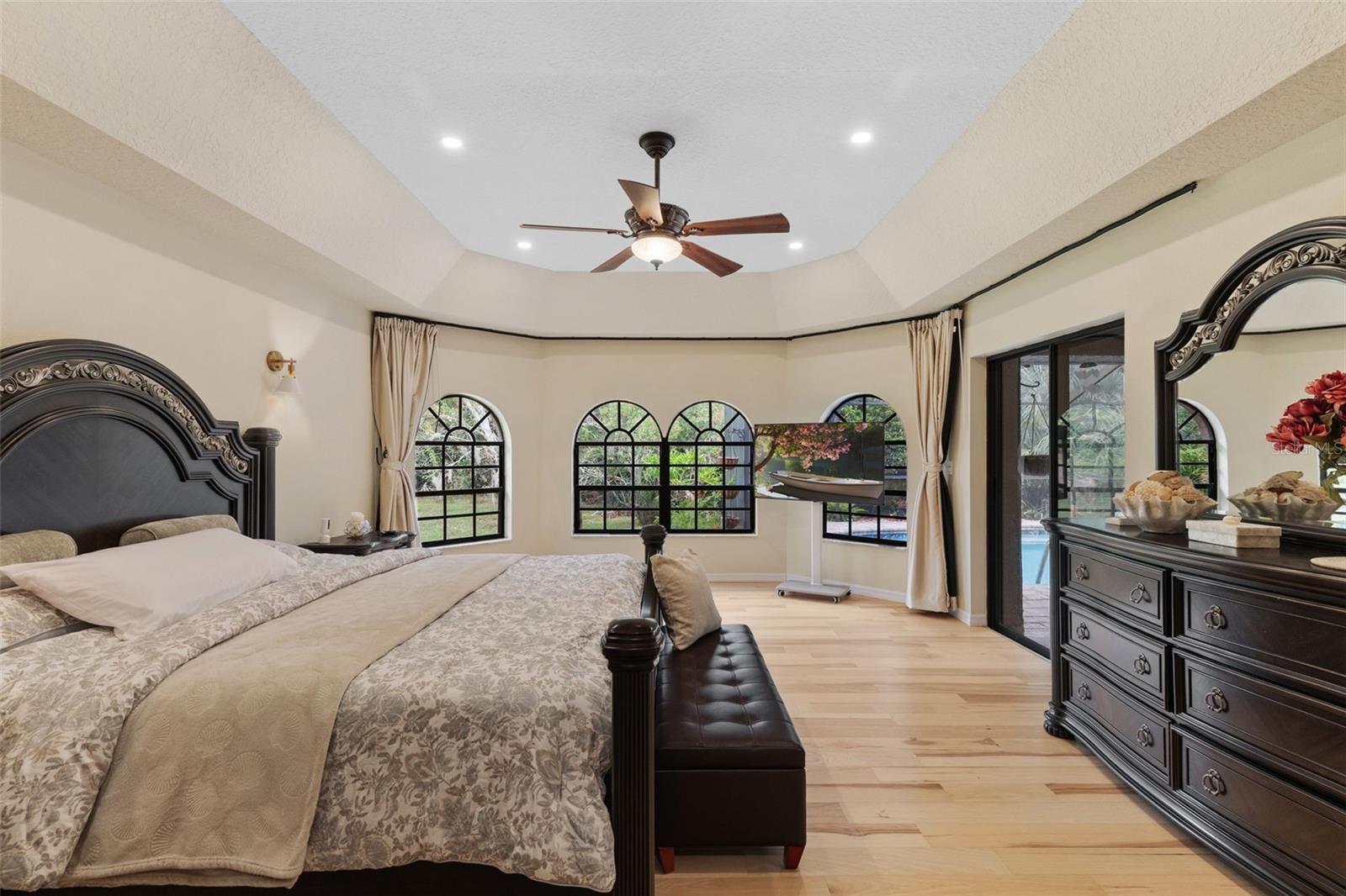 Beautiful arch top windows frame the view of tranquil yard. Private sliding doors access covered lanai area and pool.