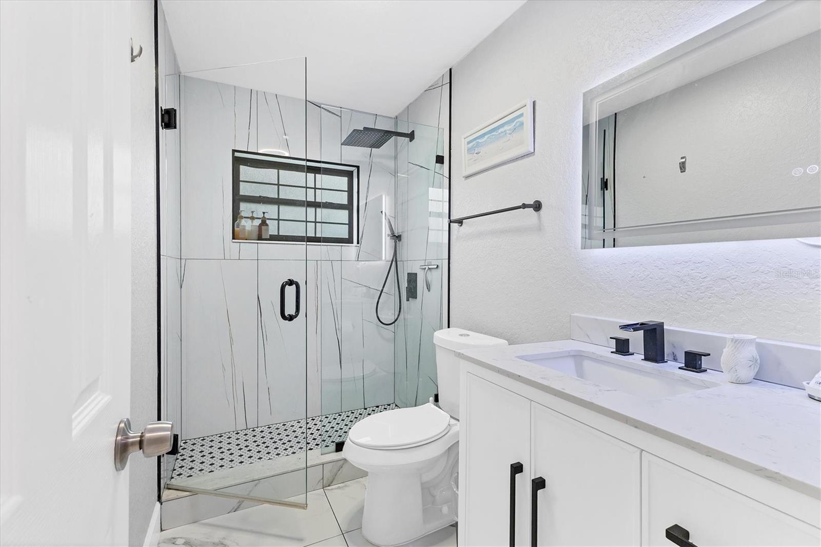 Bathroom 2 sits between bedrooms 3 & 4 and features a modern walk-in shower, granite top vanity with cabinet and drawers as well as a back lit mirror with color feature & de-fog option.