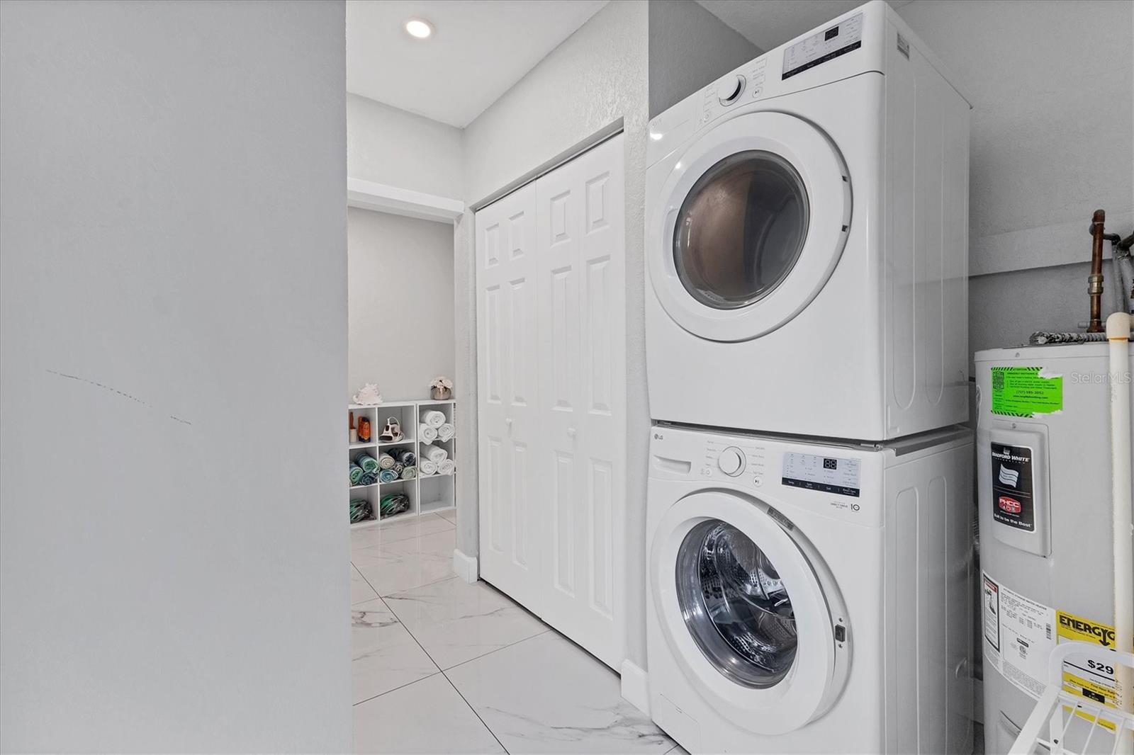 Utility room with LG washer and dryer, hot water heater and closet containing the air handler.