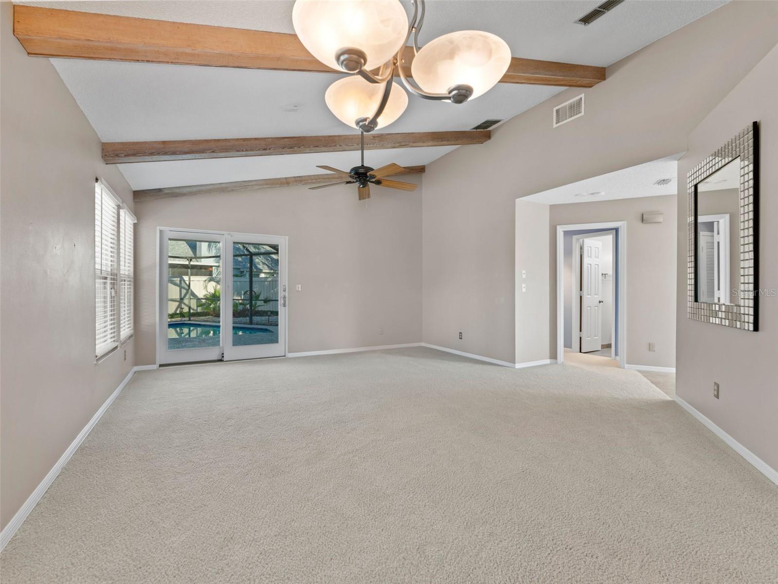 Spacious living room with hurricane-impact glass sliders that open seamlessly to the sparkling pool area