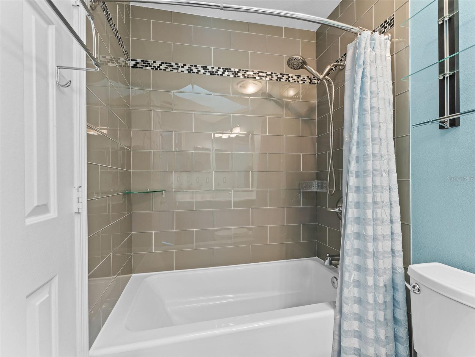 Updated tub surround with elegant glass tile finish — adding a modern, stylish touch to the bathroom