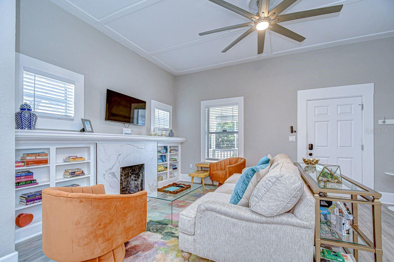 The living room welcomes you with abundant natural light, a stylish decorative fireplace, and built-in shelving for added charm.
