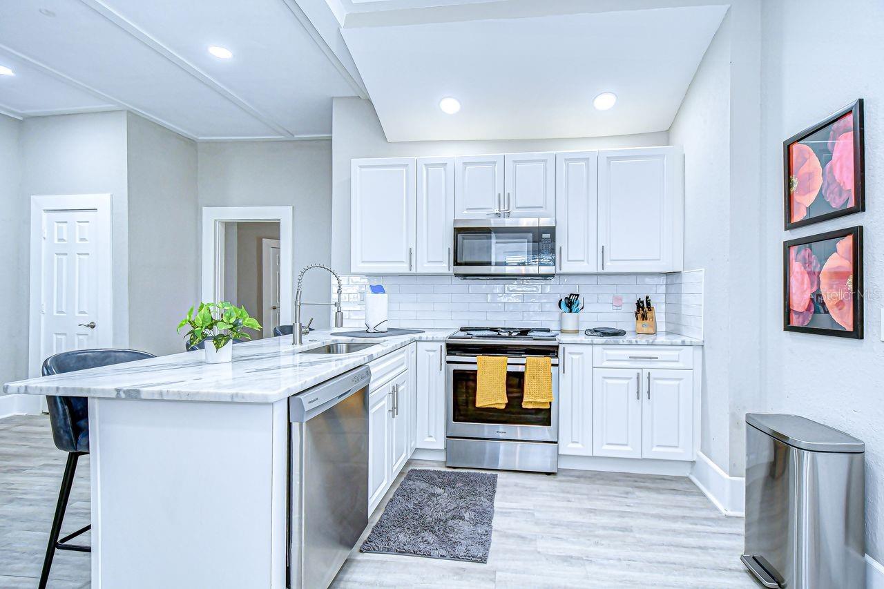 This bright and open kitchen showcases stainless steel appliances, subway tile backsplash, and ample cabinet storage.