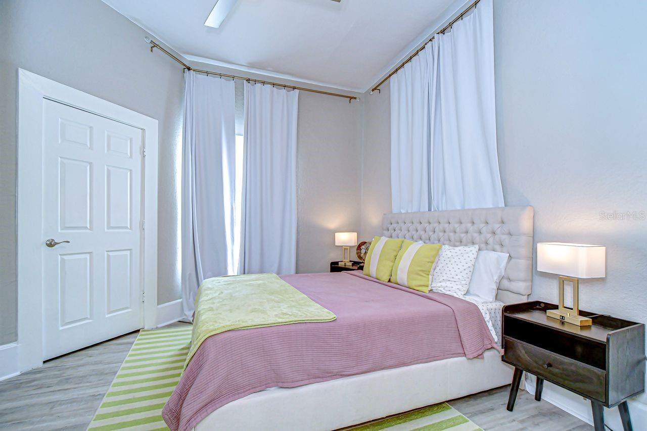 This bright and stylish bedroom features high ceilings, soft neutral tones, and plenty of natural light.
