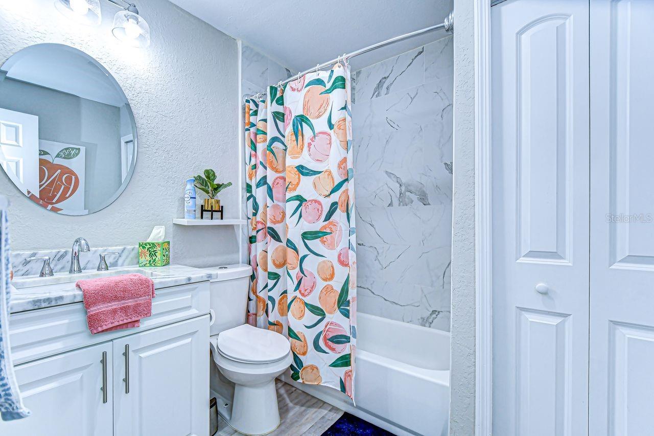 The guest bathroom features a modern marble-look vanity, updated fixtures, and a tub with stylish tile surround. Bright and functional, it’s designed with both comfort and charm in mind.