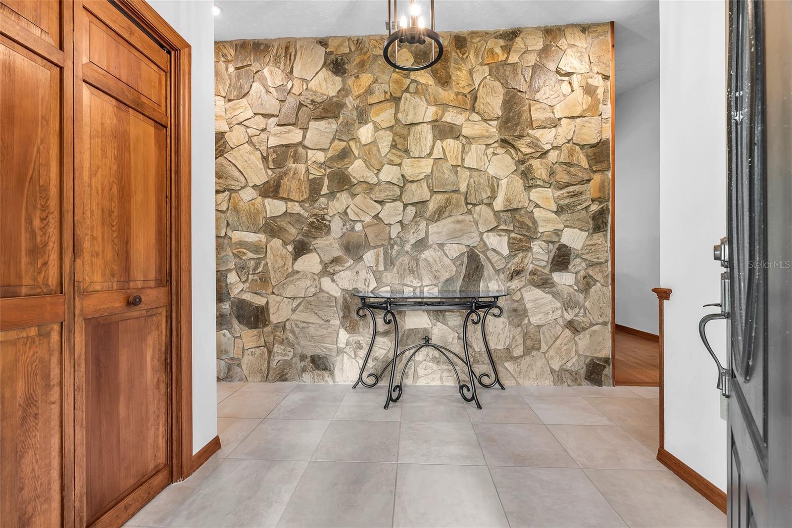 Just inside the leaded glass front door with sidelites is a stone wall feature.