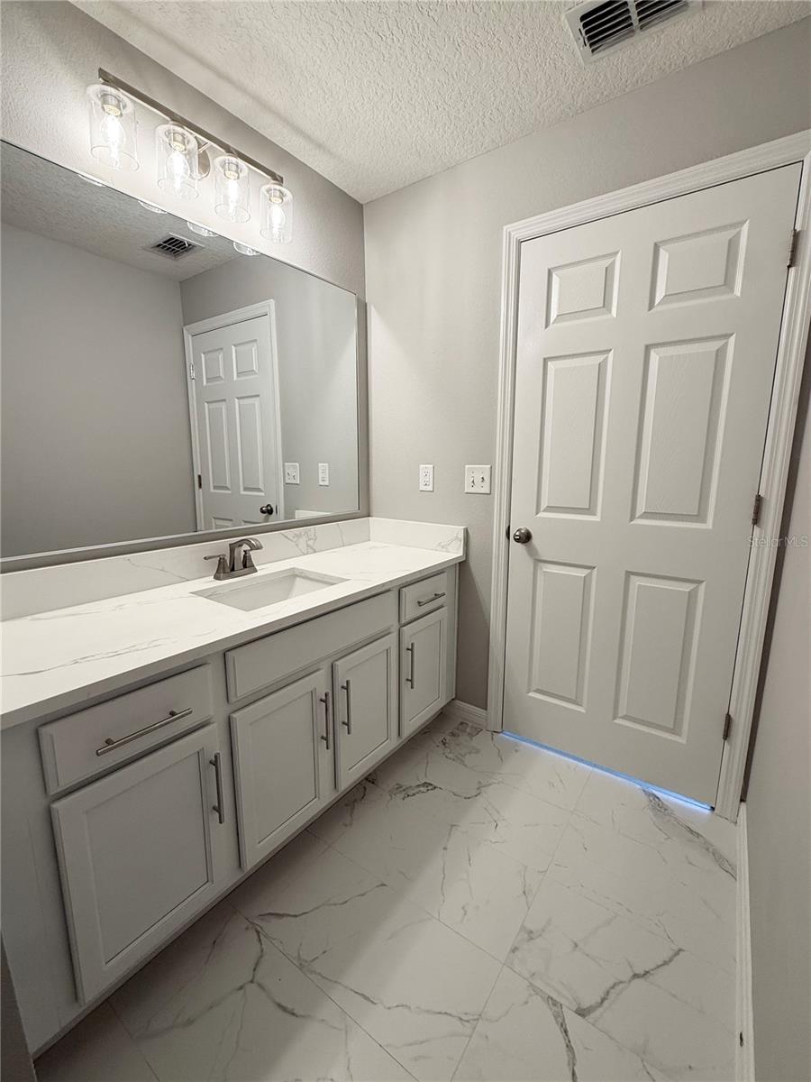 Primary bathroom exudes spa like modern feel with quartz vanity, new lighting and fixtures and newly installed marble design ceramic tile