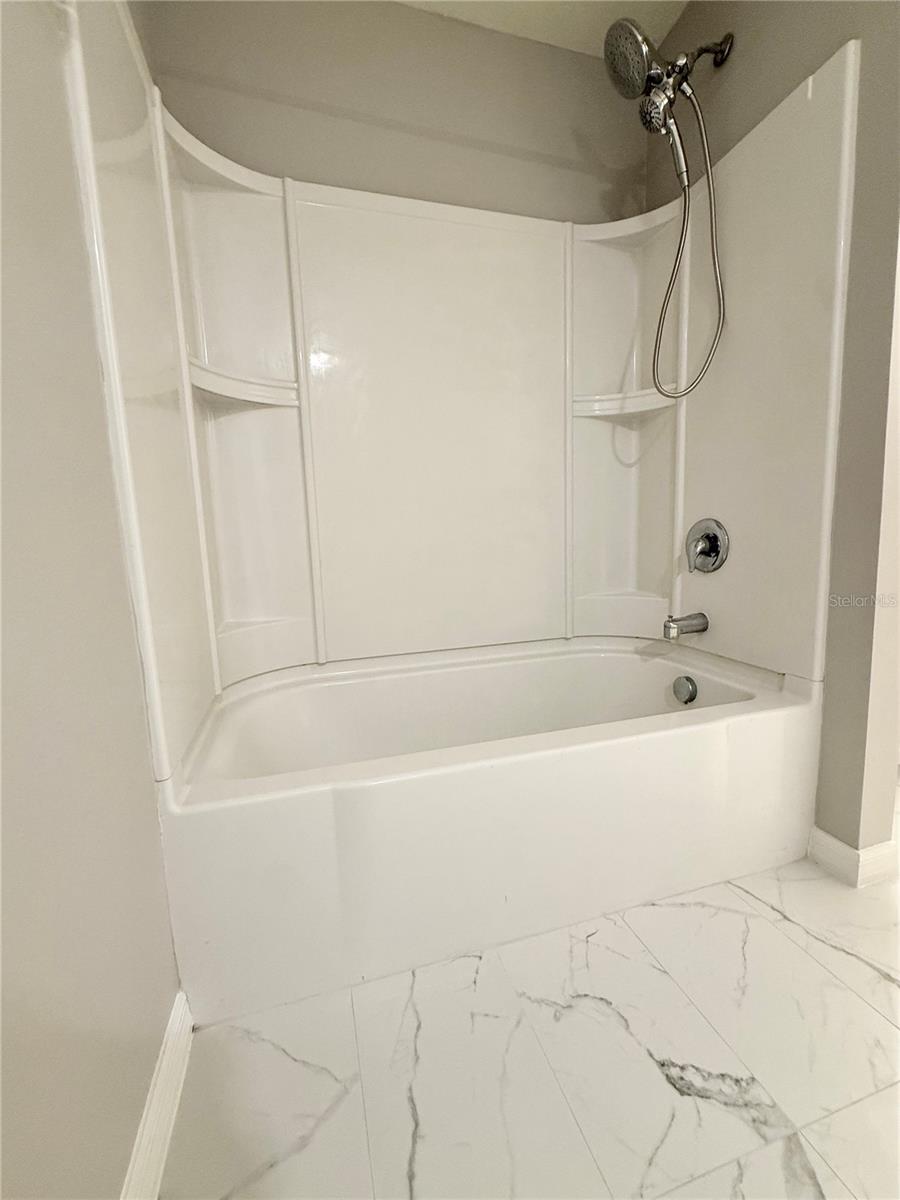 Primary bathroom exudes spa like modern feel with quartz vanity, new lighting and fixtures and newly installed marble design ceramic tile