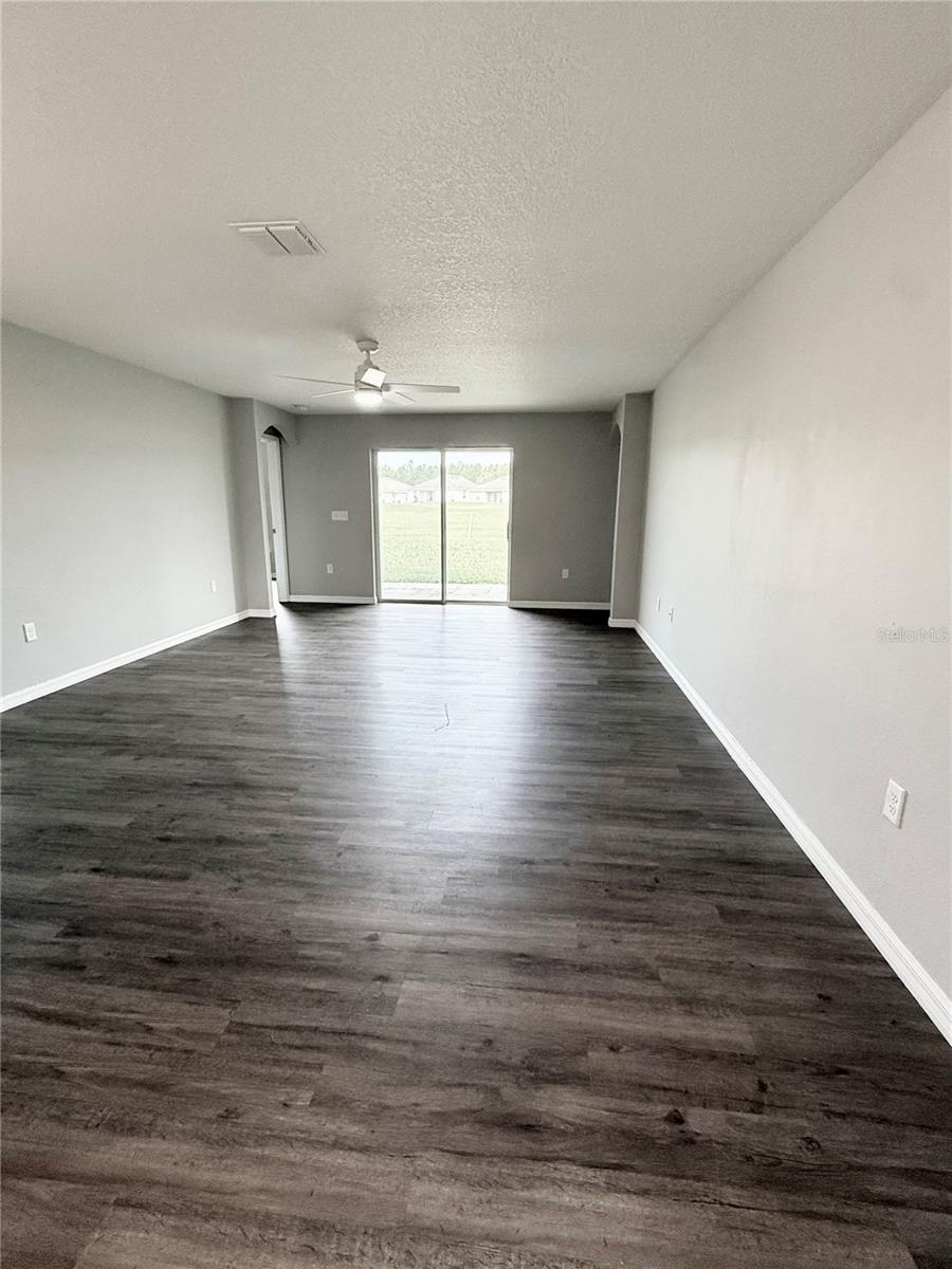Large living room with slider doors that access covered patio overlooking golf course
