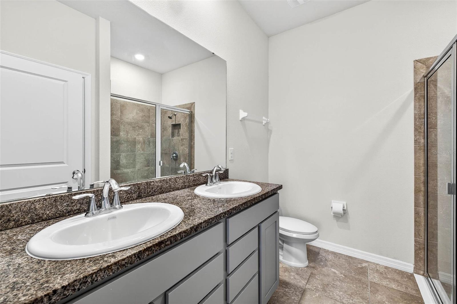 Primary ensuite bath with dual sinks, walk-in shower and linen closet.
