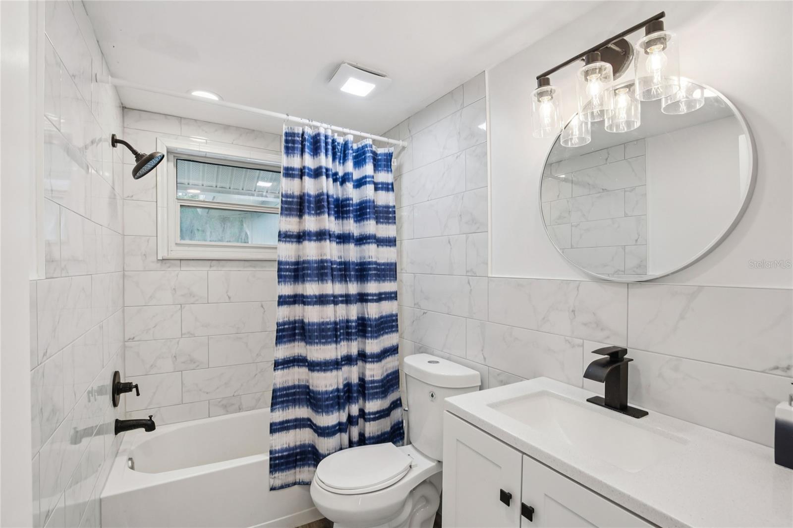Updated bathroom with modern fixtures, full tub and tiled surround
