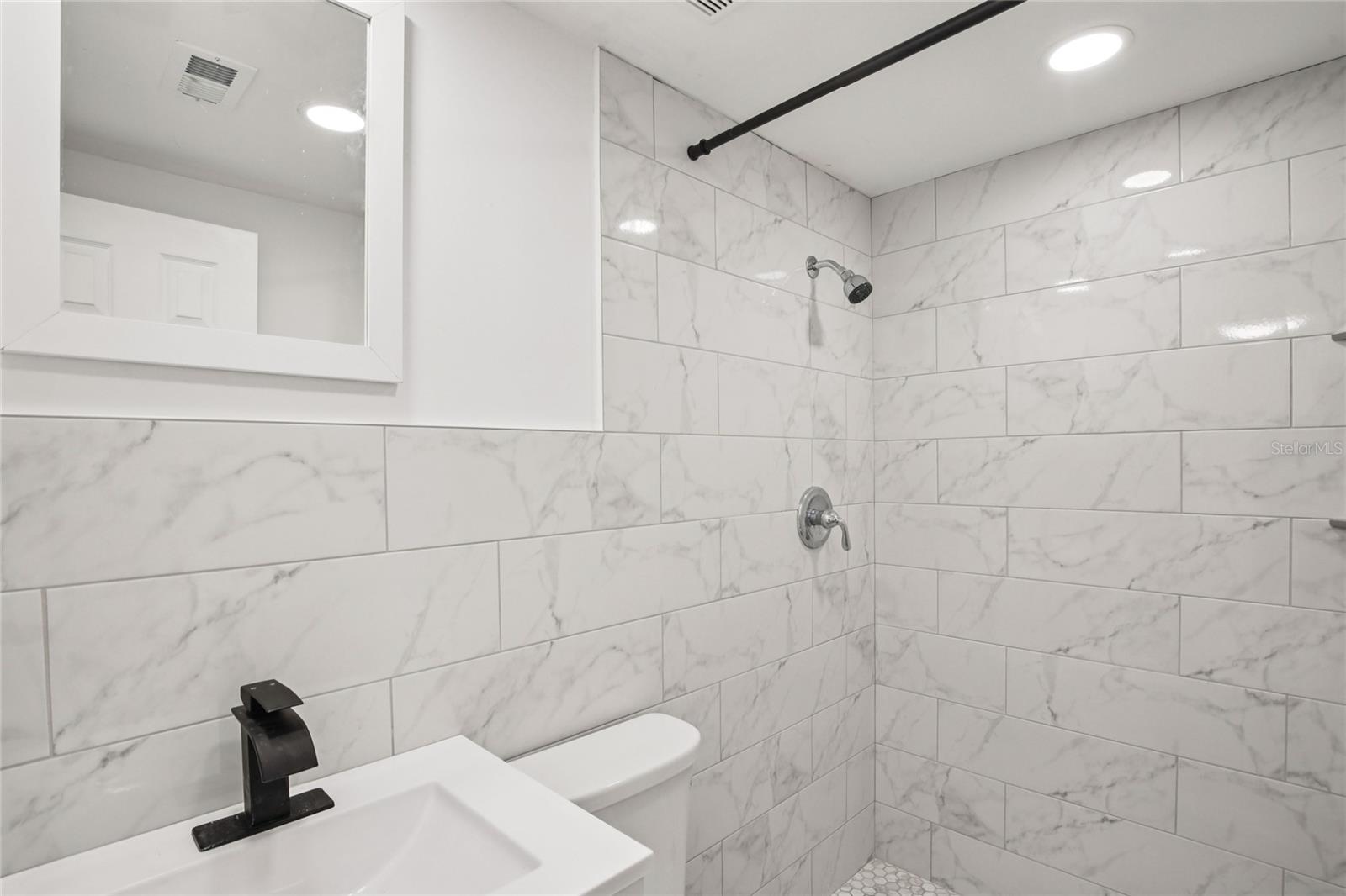 Updated bathroom with modern fixtures and tiled shower